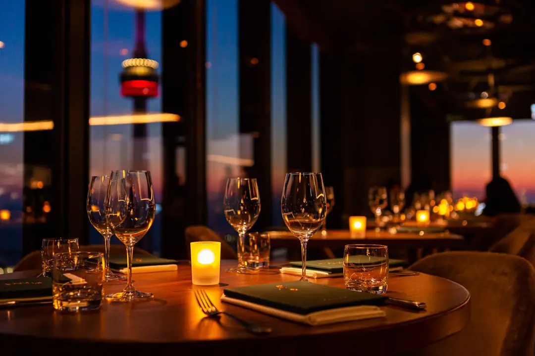 A candlelit table at Canoe at sunset, with the CN Tower through the 54th-floor windows